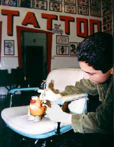Spud tenses up as the electric needle etches ink into his peel