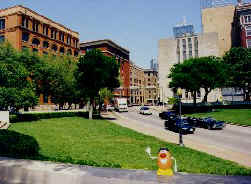 Spud stands on the grassy knoll as a '63 cadillac limo races by carrying JFK 